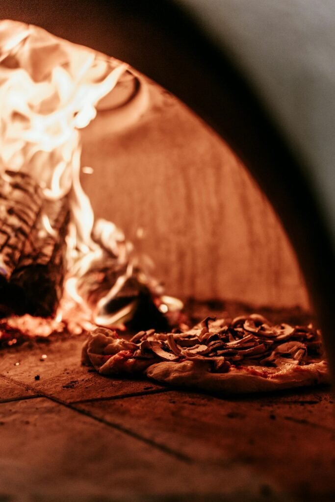 alt="Image of a pizza in a wood fire oven"