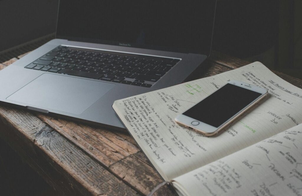 alt="Picture of Laptop smartphone open notebook with writing"