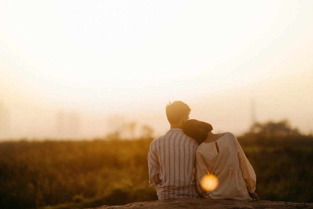 alt="Picture of Man and woman near grass field sunset"