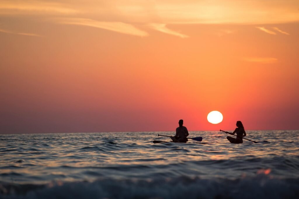 alt="Picture of Man and woman rowing in sunset"