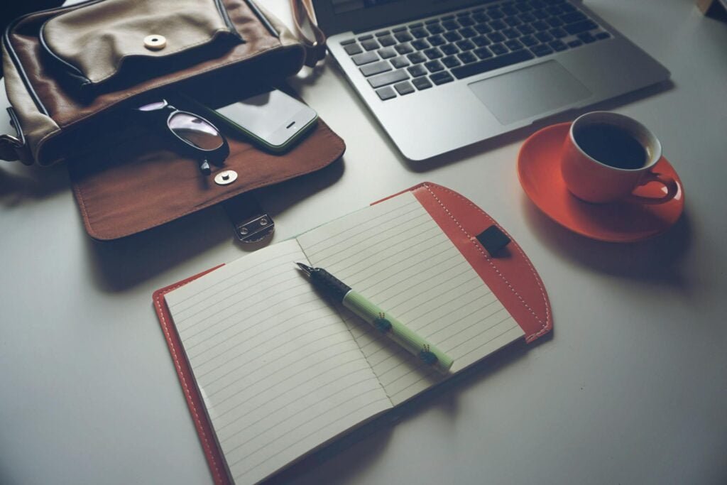 alt="Picture of Pen paper and laptop next to coffee cup"