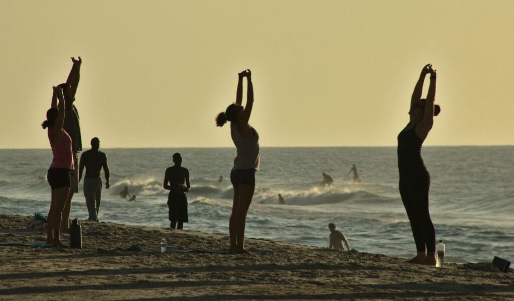 alt="Picture of People doing yoga on the beach"