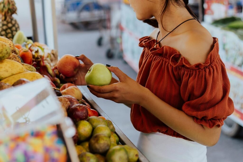 alt="Picture of Woman standing in apple market"