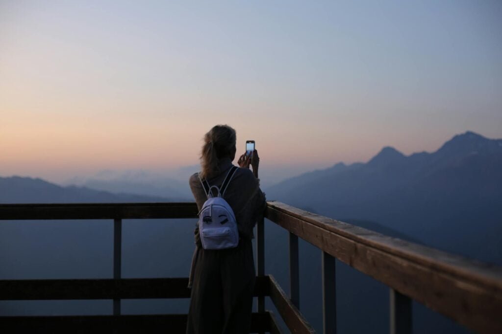 alt="Picture of Woman taking photo of mountains"