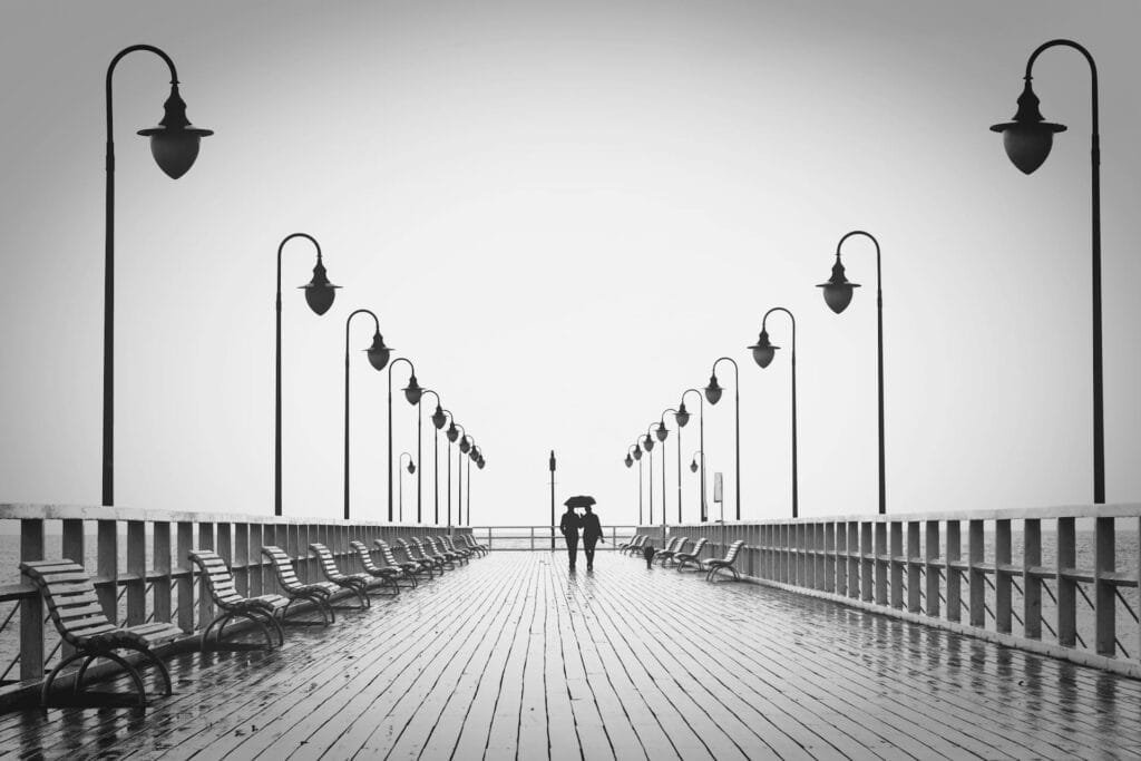 alt=”Image of Couple walking on pier in the rain”