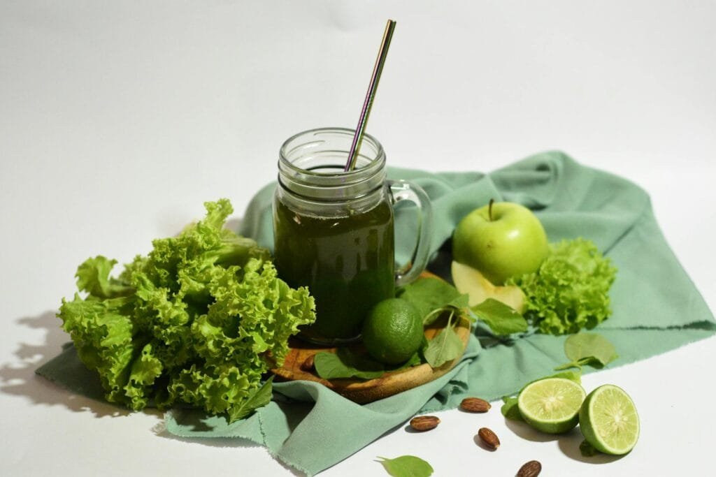alt="Image of Green smoothie in a jar next to fresh ingredients"