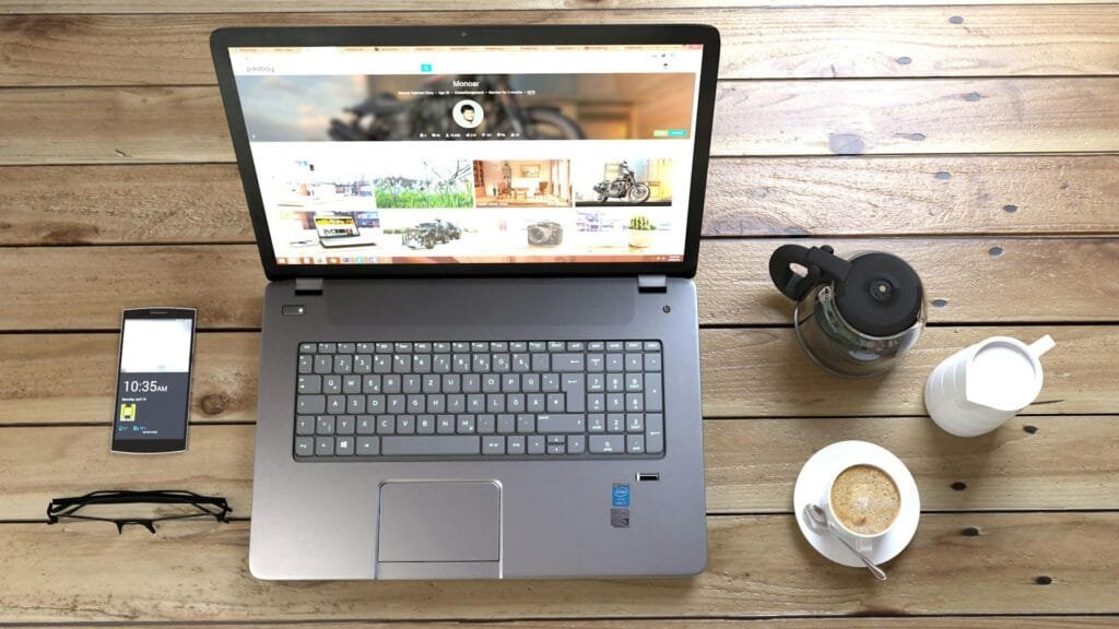 alt="Image of Laptop and smartphone next to coffee pot and cup"