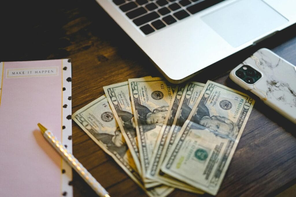 alt="Image of Laptop next to money smartphone a paper"