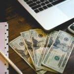 alt="Image of Laptop next to money smartphone a paper"