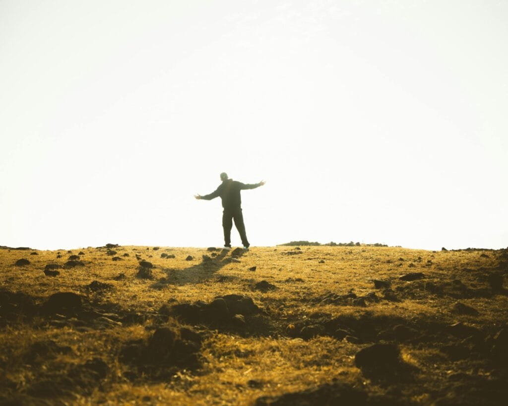 alt=”Image of Man standing in the field at sunset”