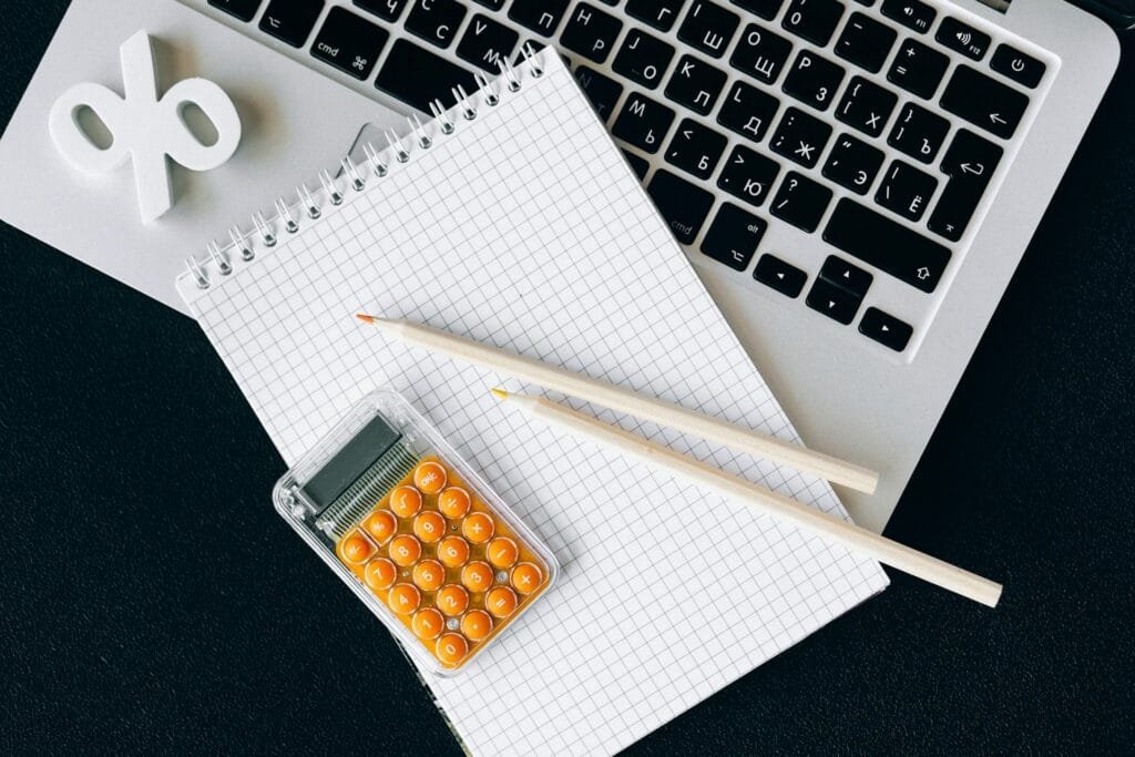 alt="Image of Open laptop with paper calculator and percent symbol"