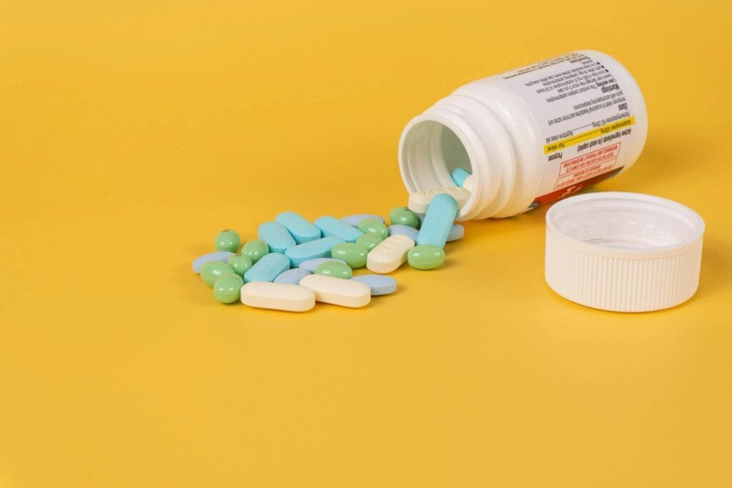 alt="Image of Open medicine bottle with medicine on surface"