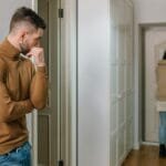 alt=”Image of Woman walking out the door with a black bag”