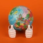 alt=”Image of A globe with a thumbs up figurine”