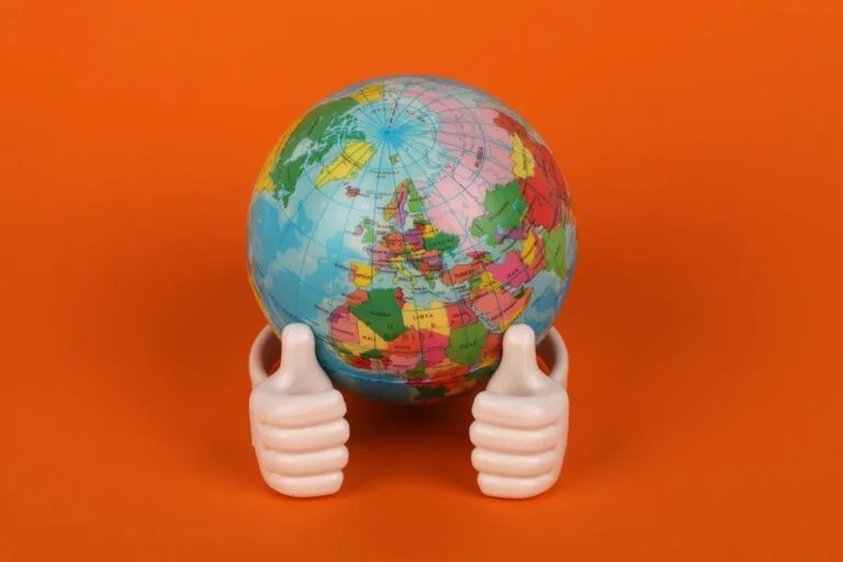 alt=”Image of A globe with a thumbs up figurine”