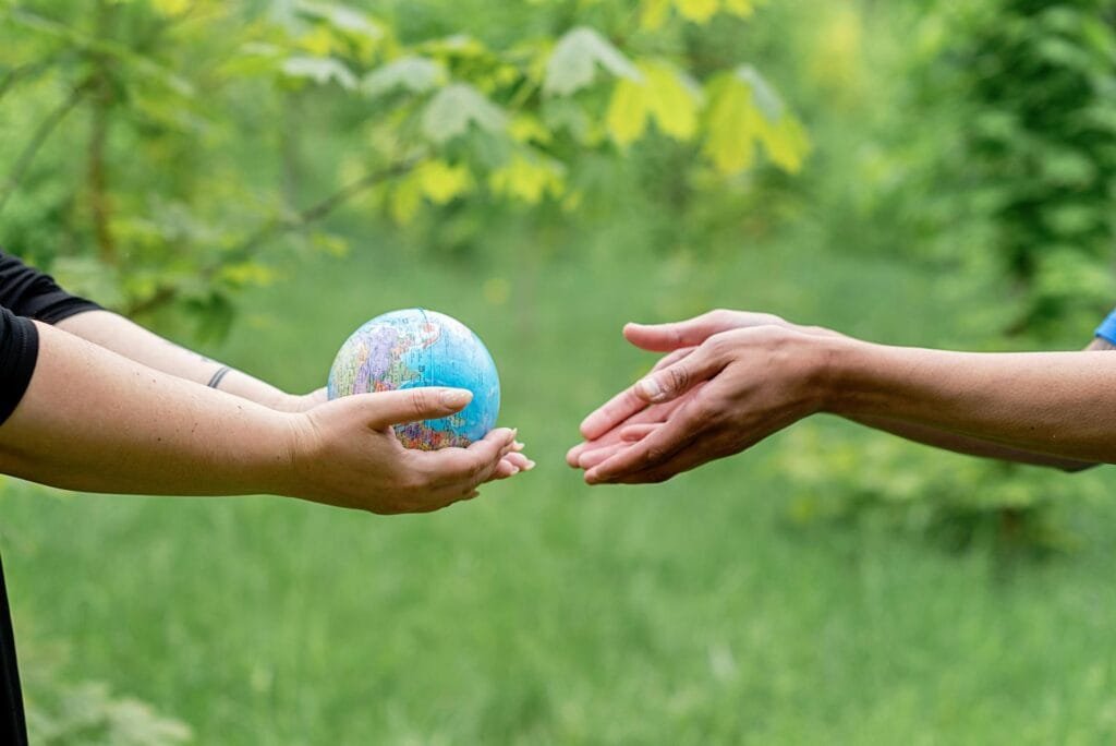 alt=”Image of Hands passing the globe to another”