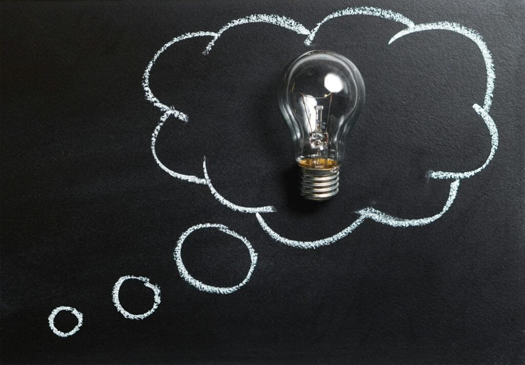 alt=”Image of Lightbulb on a black board”