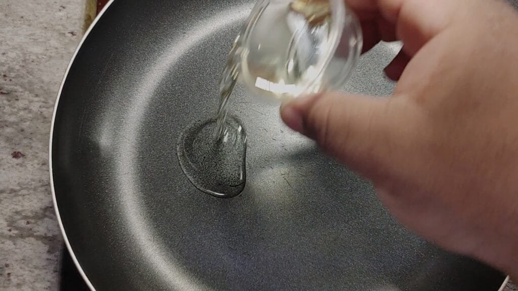 alt="Adding Canola Oil to frying pan"