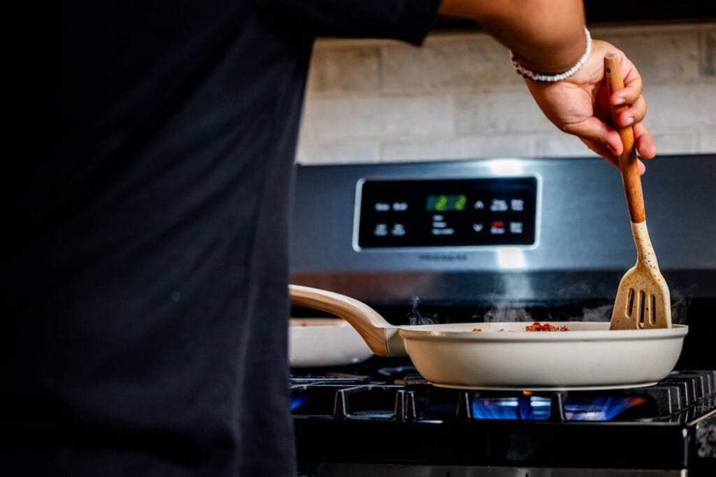 alt="Hand stirring a frying pan"