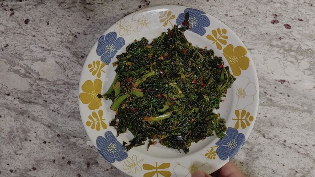 alt="Hand picking up a plate of Kale stir fry"