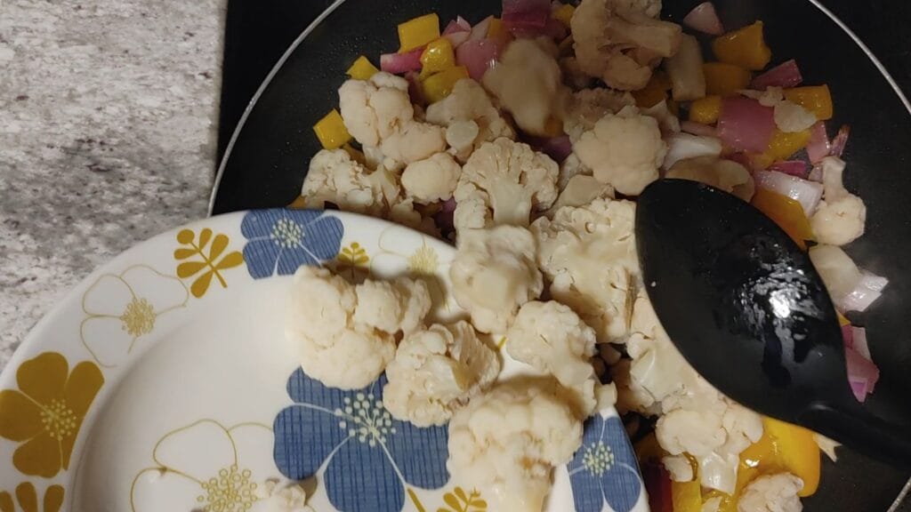 alt="Adding Cauliflower to pan"