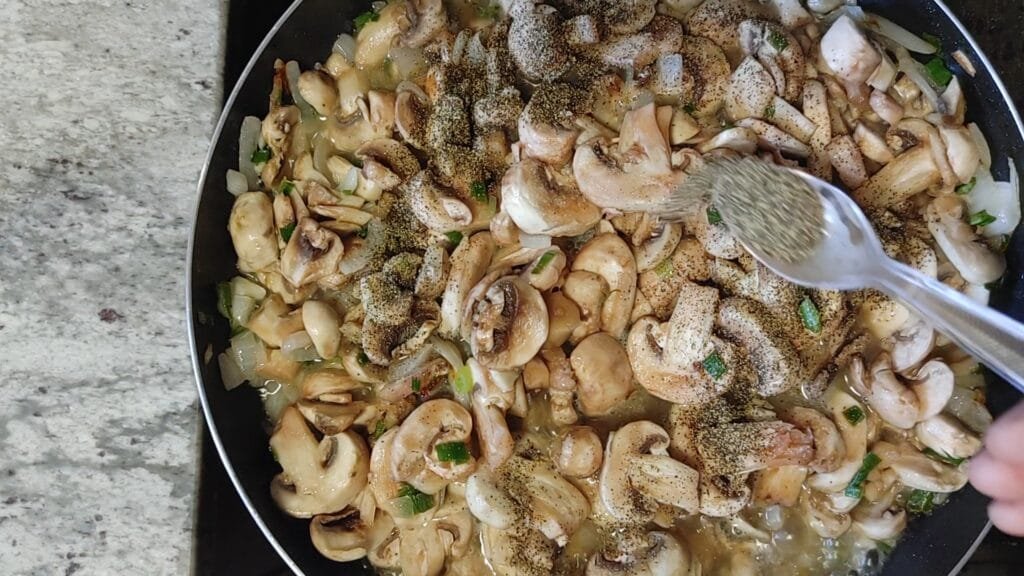 alt="Adding black pepper to pan"