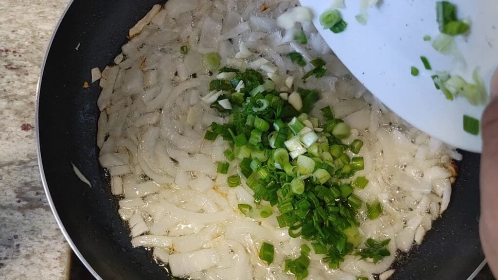 alt="Adding green onions to frying pan"
