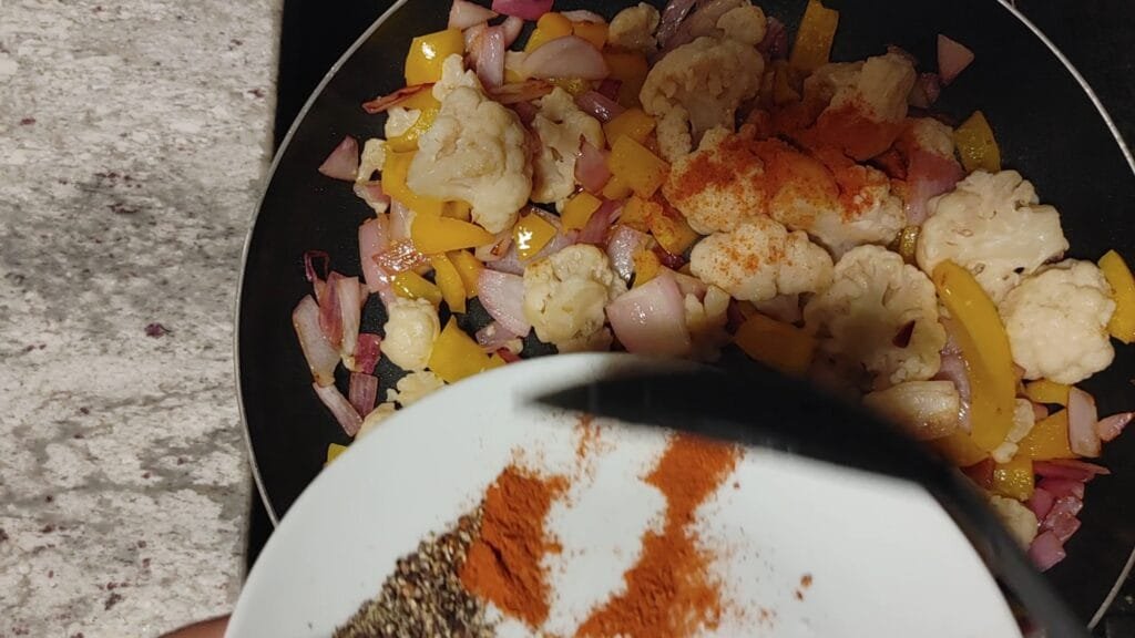 alt="Adding red pepper to pan"