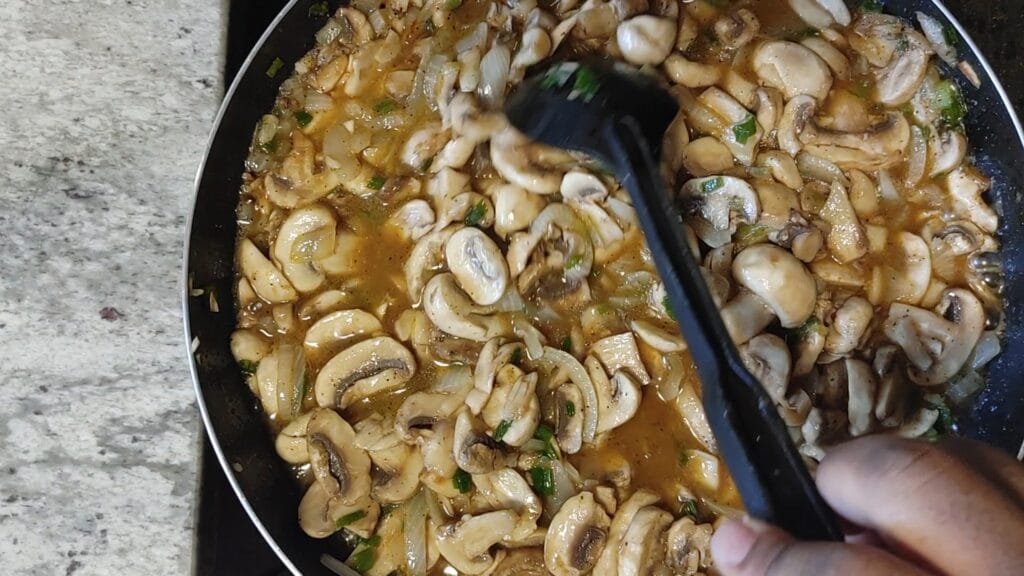 alt="Stirring Sauteed mushroom in pan"